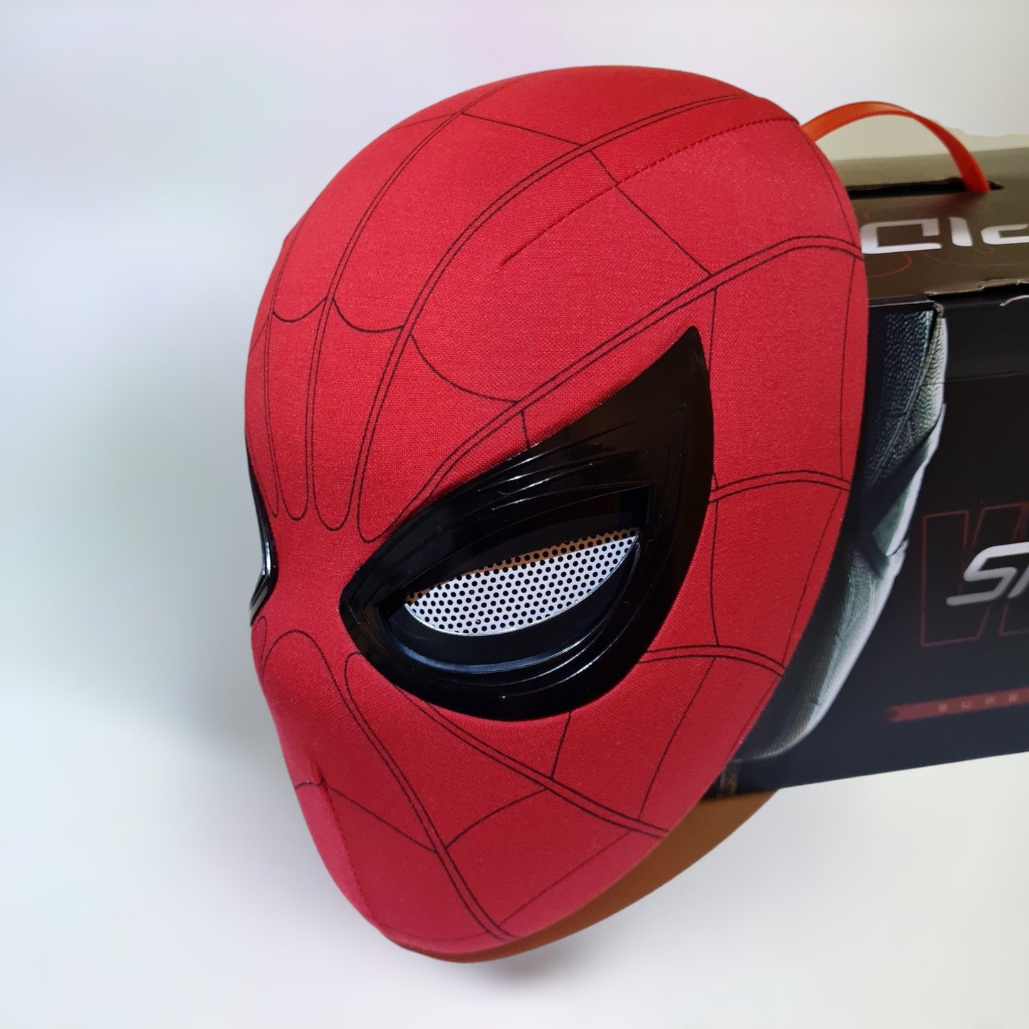 Spiderman mask with blinking movable eyes realistic ring remote control and box on a plain white background.
